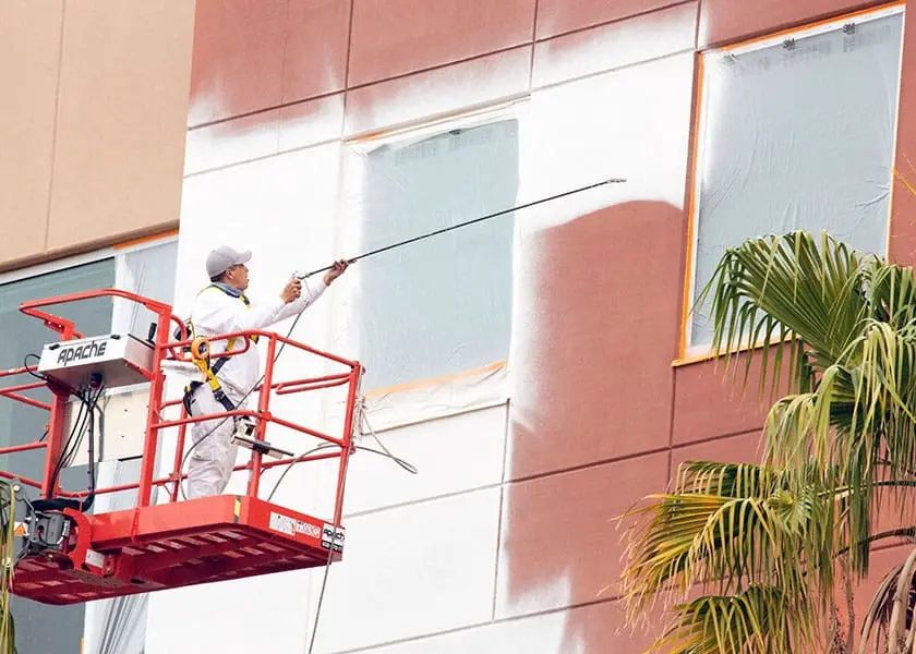 Ghaster painter using spray paint to paint the side of a building.