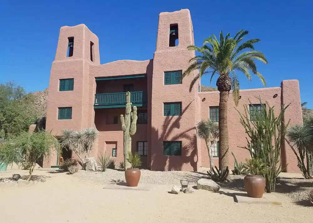A building with a fresh coat of paint, surrounded by palm trees and lush plants.