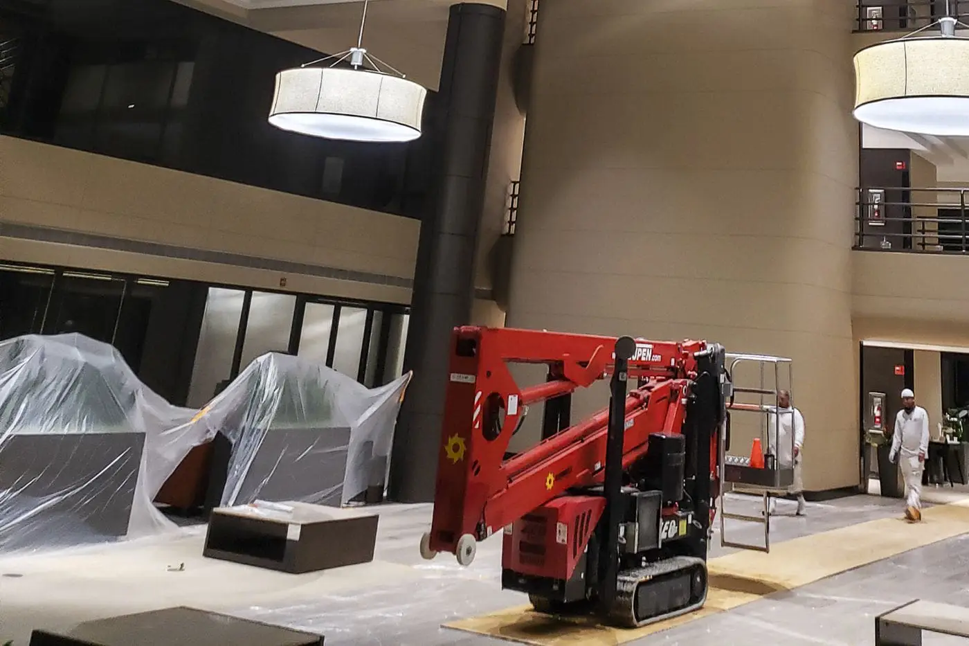Inside a commercial building, painters setting up their machine lift to paint, highlighting their equipment and professional approach to the job.