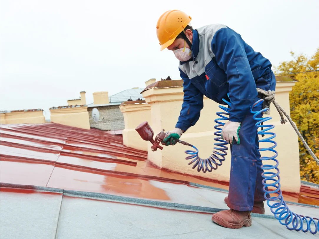 Contractor spray painting a roof