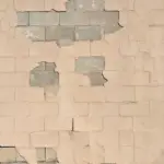 Peeling paint on concrete block wall with exposed masonry and surface cracking