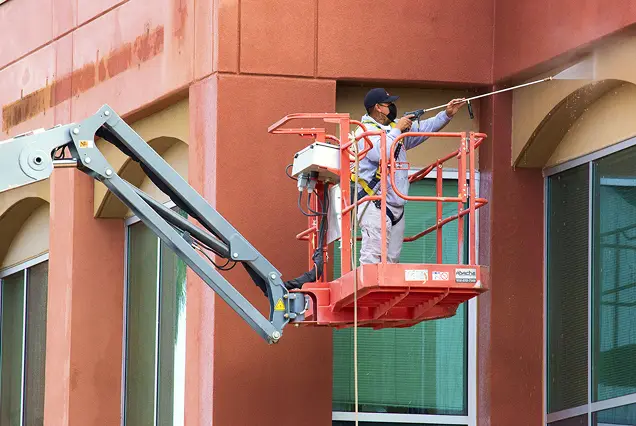 Professional exterior painting on commercial building using boom lift