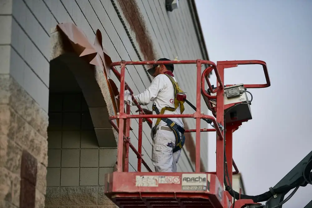 Commercial painter applying exterior coating from aerial lift